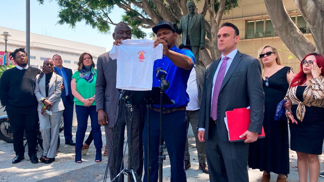 Jonathan Wright, 39, holds up the T-shirt he was given when he first went to MacLaren Children's Center in El Monte as an 8-year-old during a news conference in Los Angeles, June 9, 2022. (AP Photo/Christopher Weber, File)