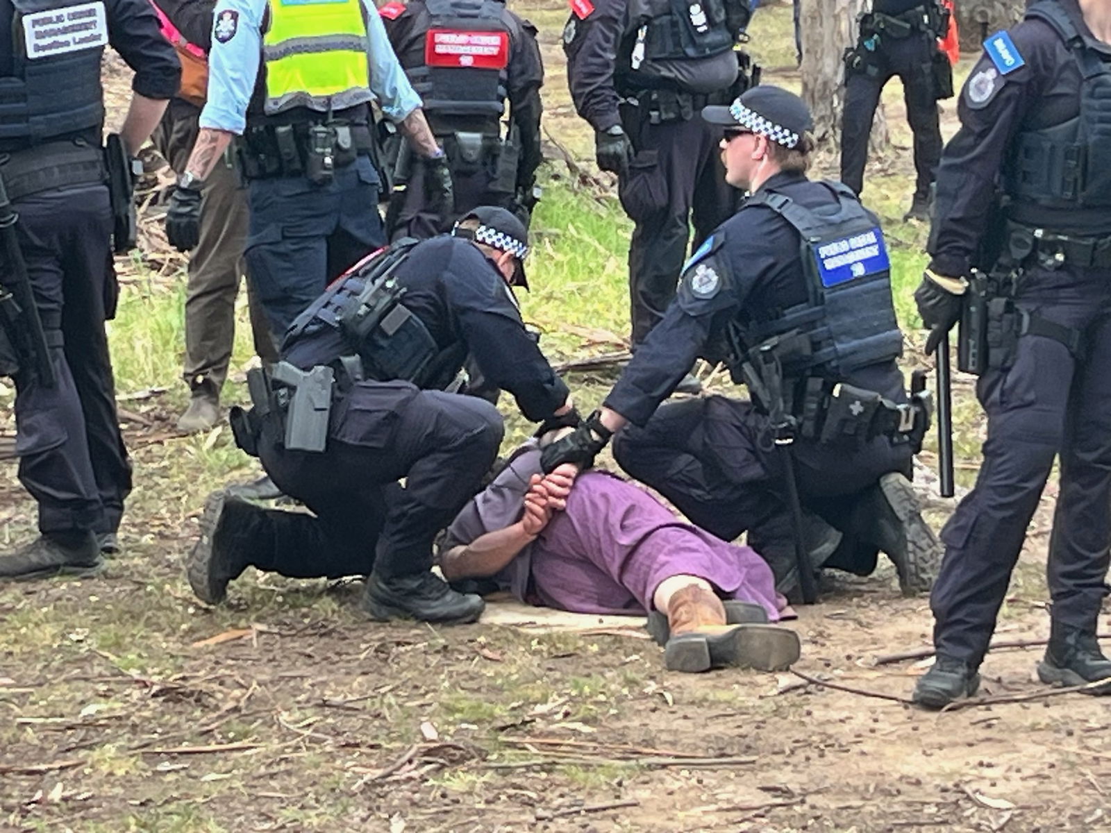 A person on the ground with police beside them.
