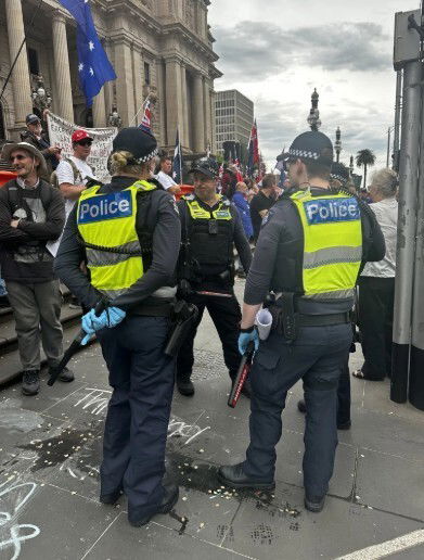Two police officers standing among protesters in Melbourne