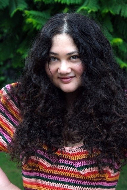 A woman with long dark curly hair and a striped top