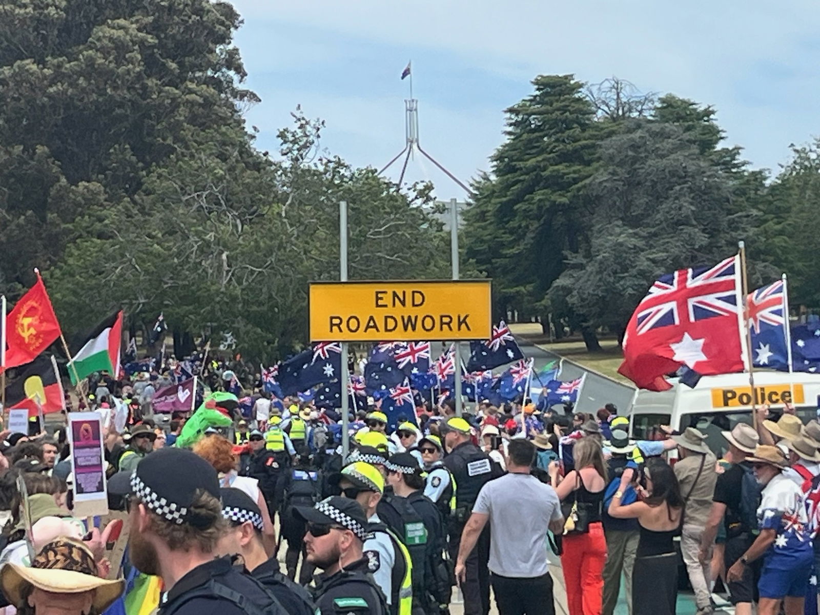 A group of protestors marching with parliament house in the background.