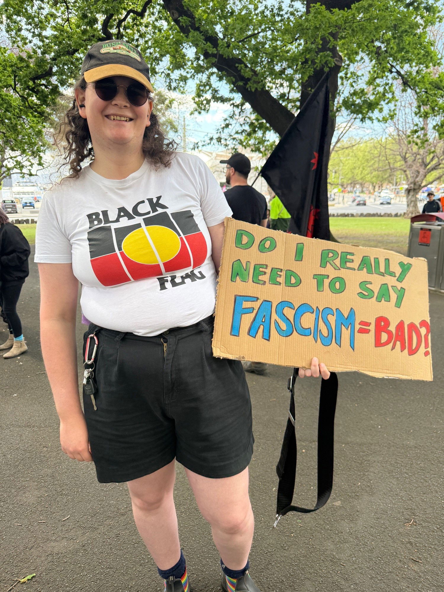 Rosie Brennan stands with a sign that says, Do I really need to say fascism = bad?