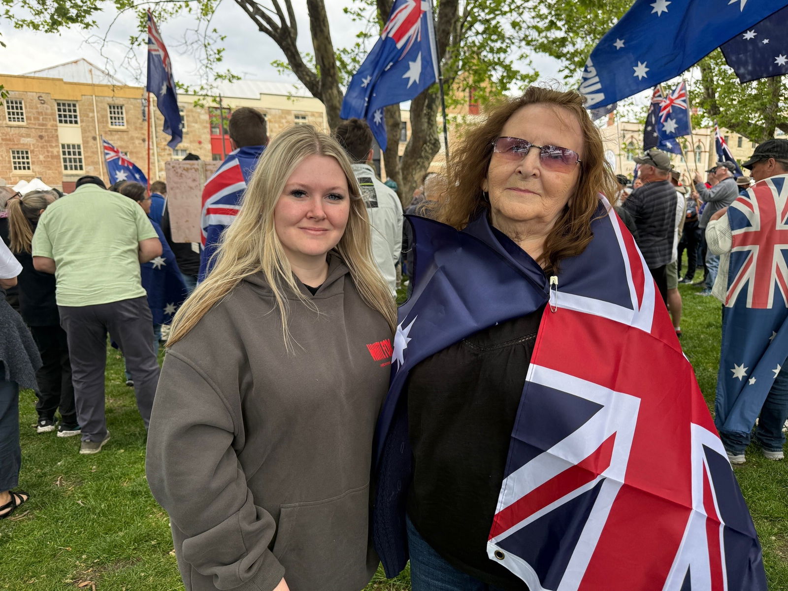 Julia Pycroft wearing an Australian flag as a cape stands with her granddaughter