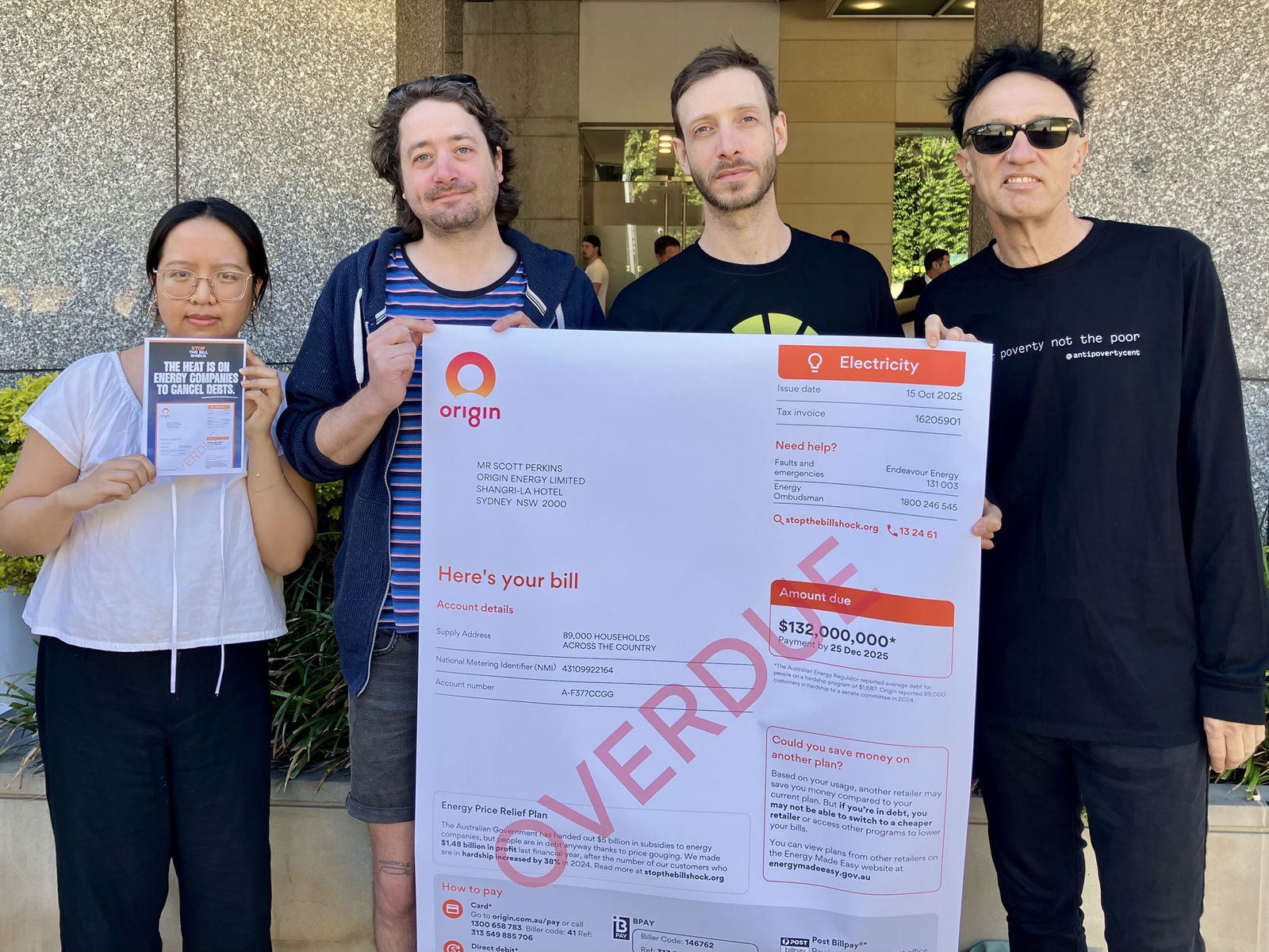 People hold a large mock energy bill with 'OVERDUE' written on it in red