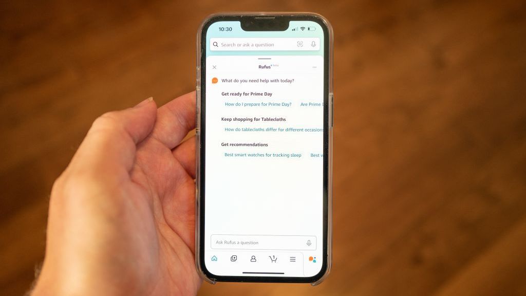 Person's hand holding an iPhone and using the Amazon Rufus AI system