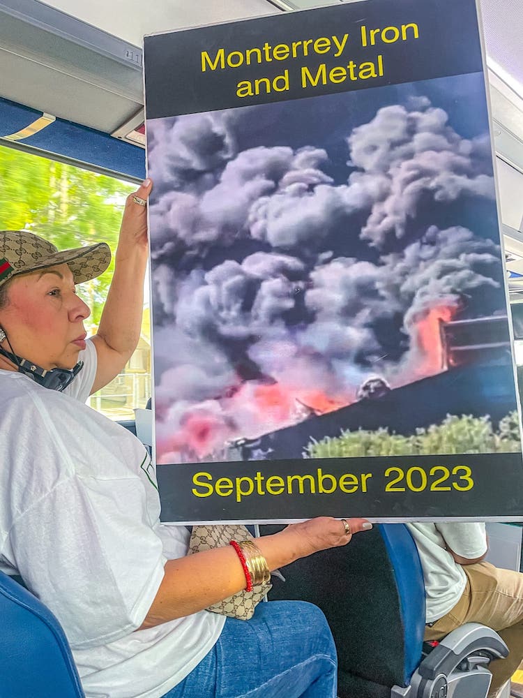A resident holds up a poster documenting recent fires at a local metal recycling yard during a “toxic tour” of San Antonio’s South Side.