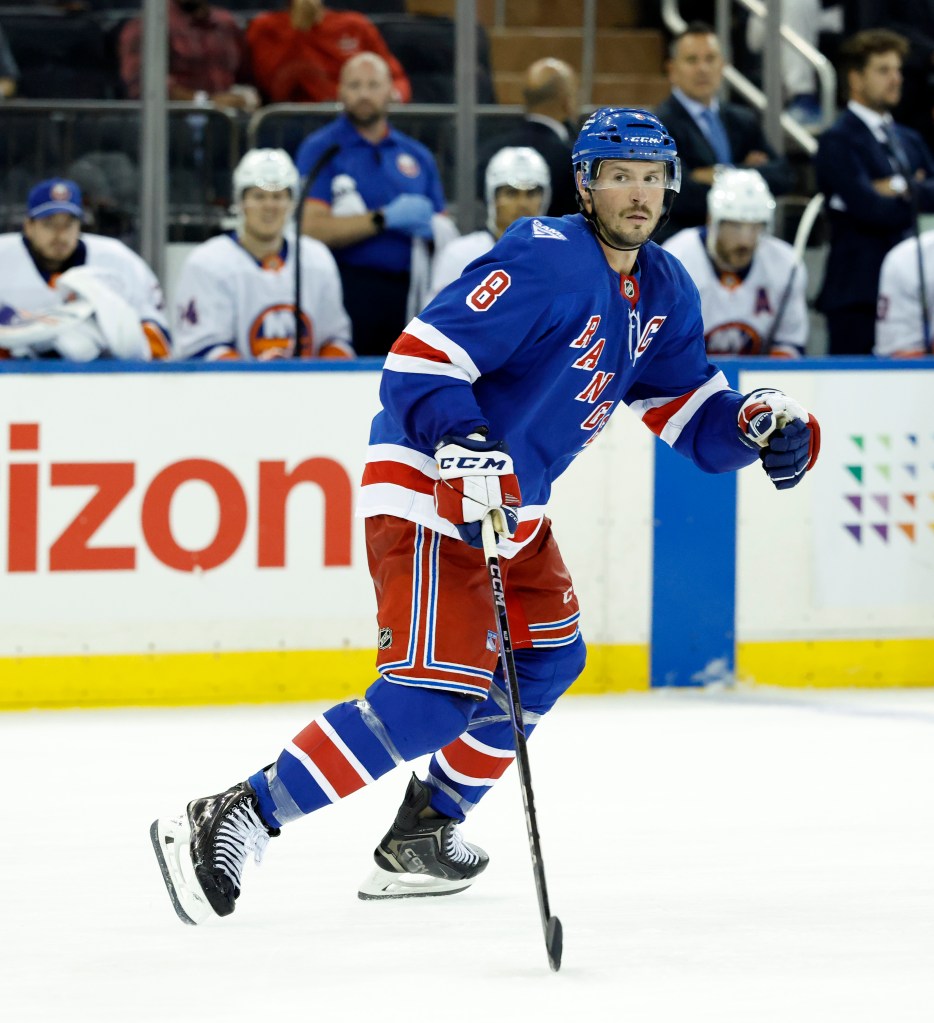 J.T. Miller of the New York Rangers skating on ice in front of the New York Islanders bench.