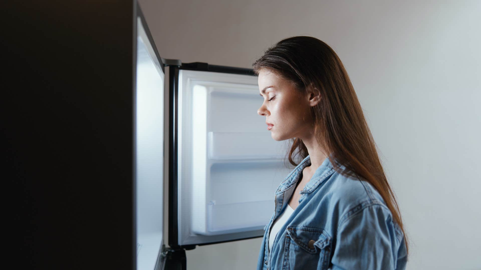 woman looking in empty freezer and fridge