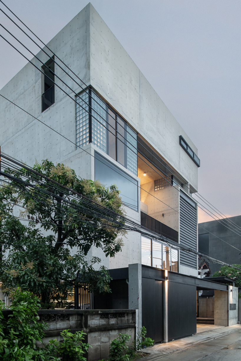 green courtyard anchors hybrid home and office within concrete structure in bangkok