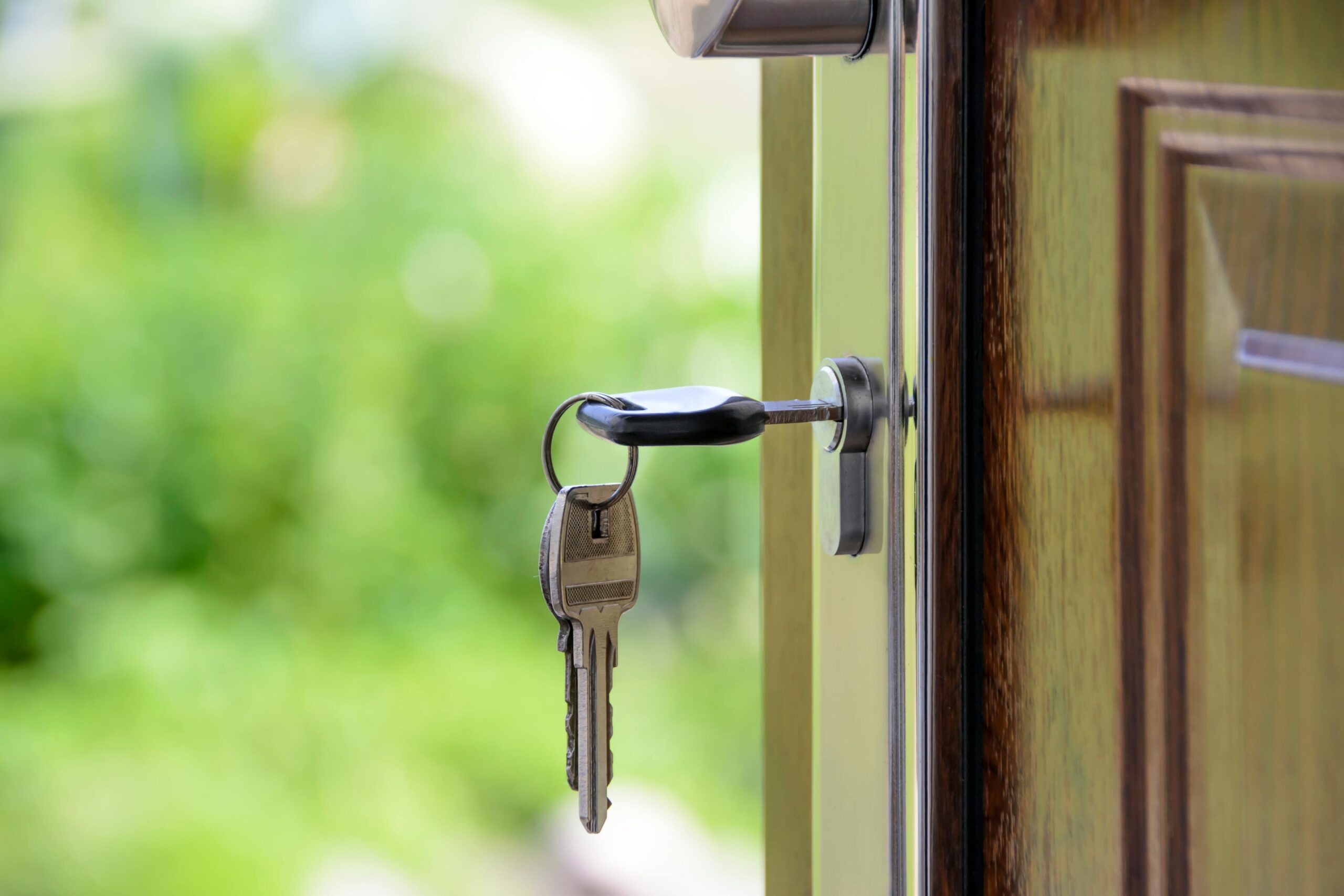 Keys hanging out of the lock in the front door of a house