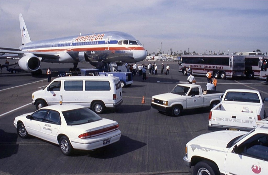 An American Airlines plane and several white vans on the tarmac at Phoenix Sky Harbor Airport.