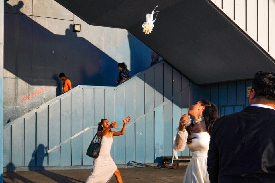 a woman anticipates catching flowers being thrown her way at a bouquet toss