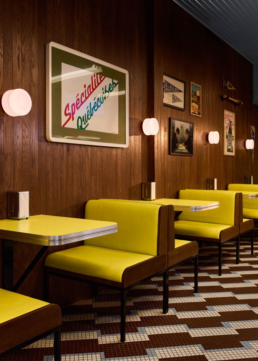 Row of bright yellow booth seating and matching tabletops against a dark wood wall