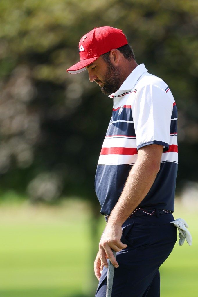 Scottie Scheffler in a red cap and patriotic polo shirt, holding a golf club, during the 2025 Ryder Cup.