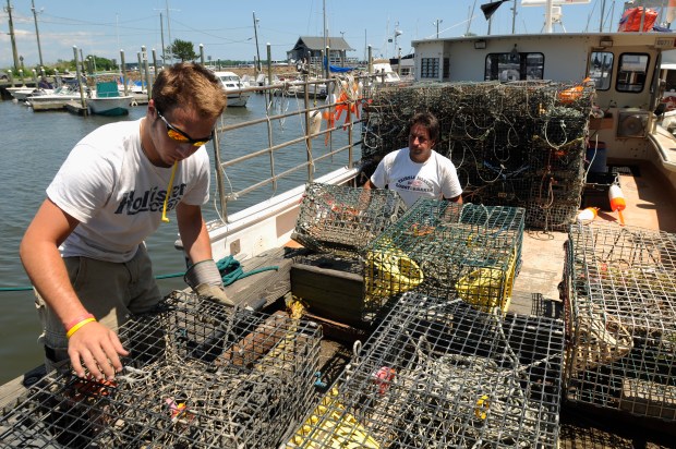 Lobsterman Bart Mansi III and his son, Bart Mansi IV, at left, load about 120 lobster pots onto his boat, the Erica Paige, at the Guilford Lobster Pound on June 25, 2008. Mansi was preparing to set the pots for the summer season early the next morning. (Bob MacDonnell/Hartford Courant file)