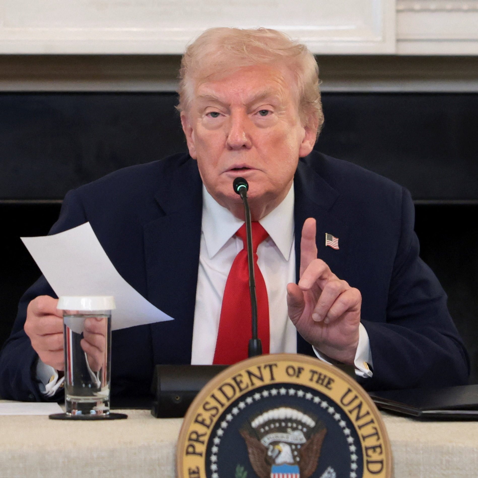 Donald Trump holds a note and speaks during a roundtable.
