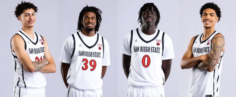 Four young men in white basketball uniforms with red lettering stand side-by-side. They play for SDSU.