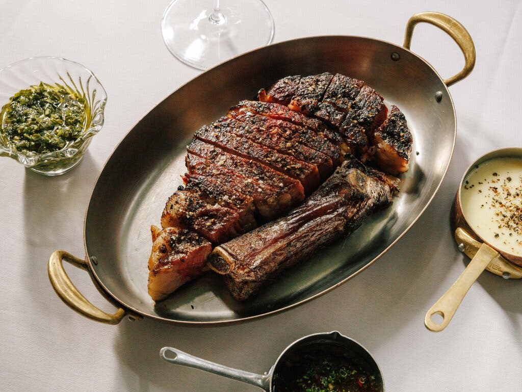 A steak sliced off the bone with sauces on the side.