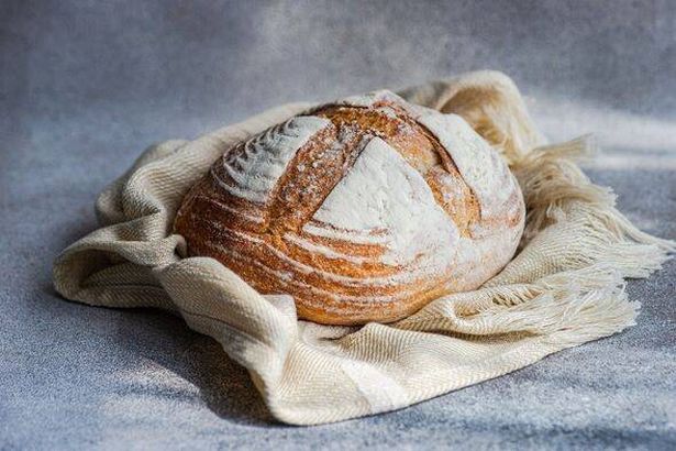 Close-up of a loaf of homemade sourdough bread on a kitchen worktop in sunlight