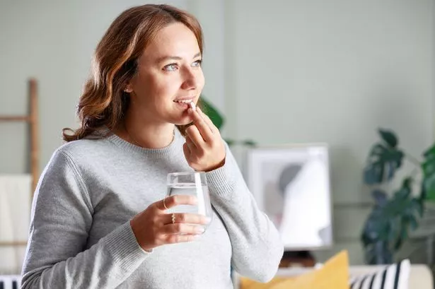 Smiling young woman taking medication at home