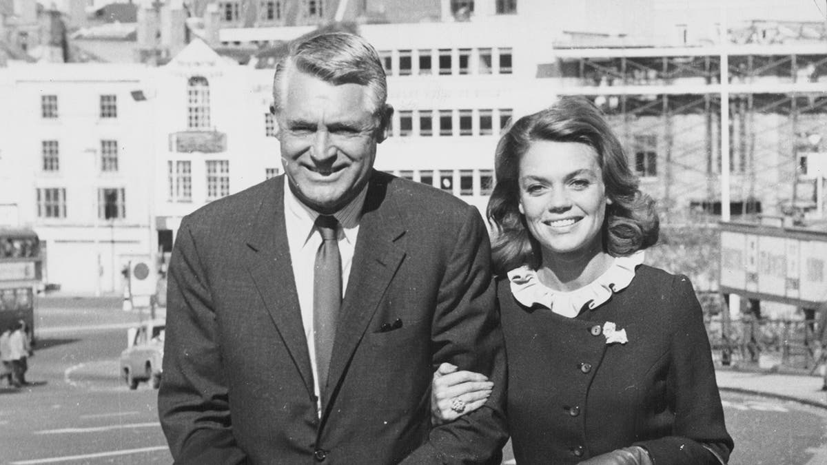 Dyan Cannon and then-husband, Cary Grant, walking in arm together smiling.