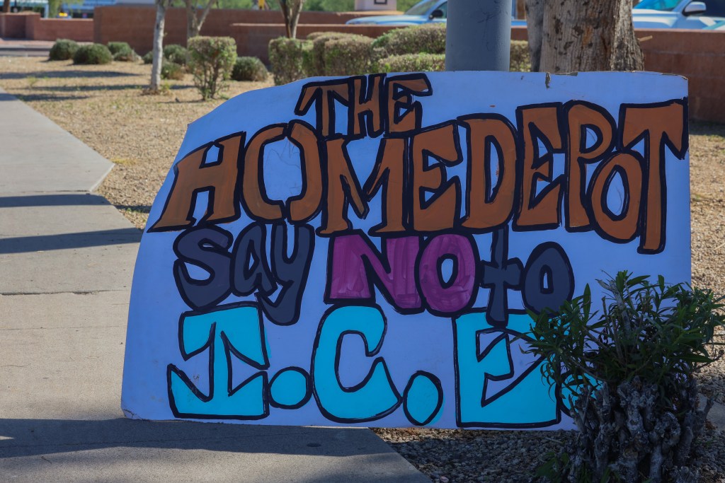 A protest sign condemning ICE raids at Home Depot sits along Thomas Road.