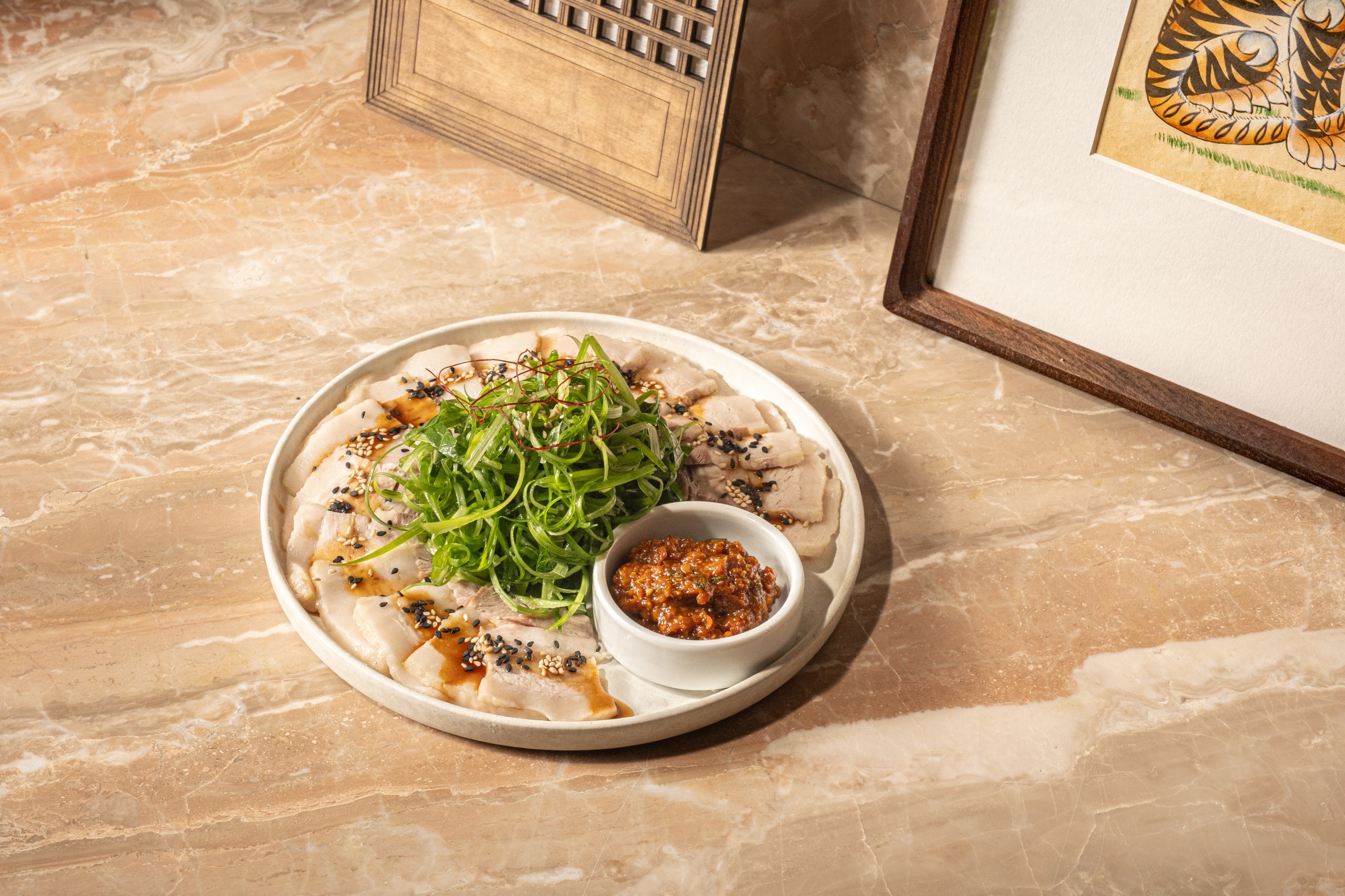 Sliced pork belly on a plate sitting on a counter at Hojokban