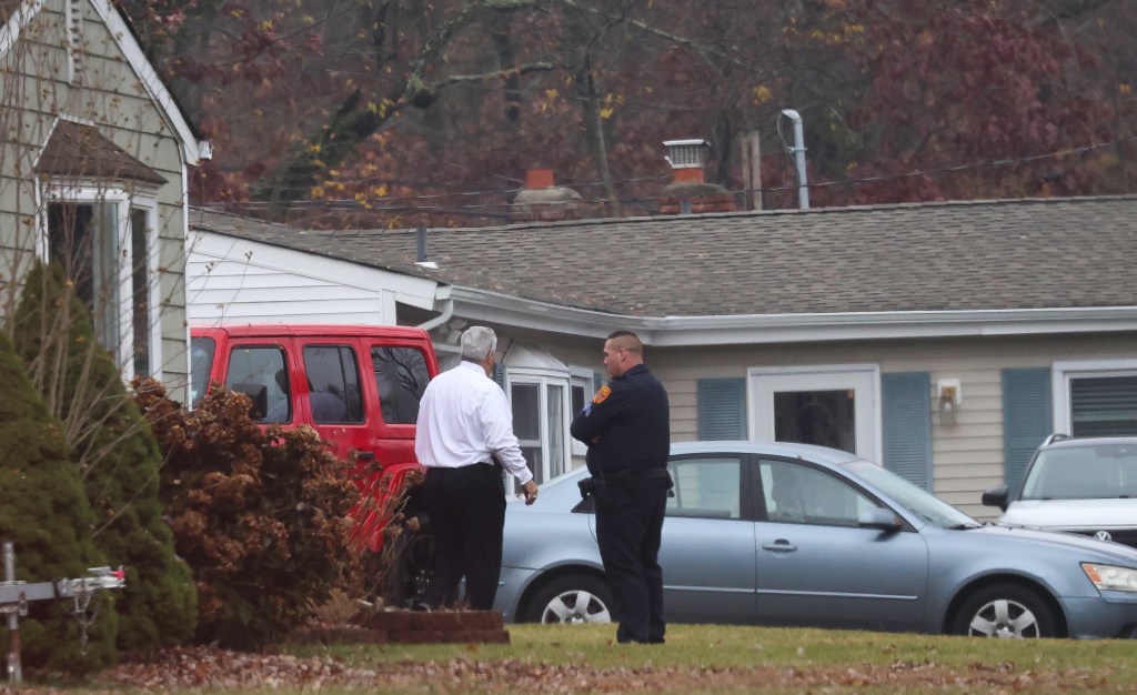 A police officer and another man stand near cars parked in a yard.