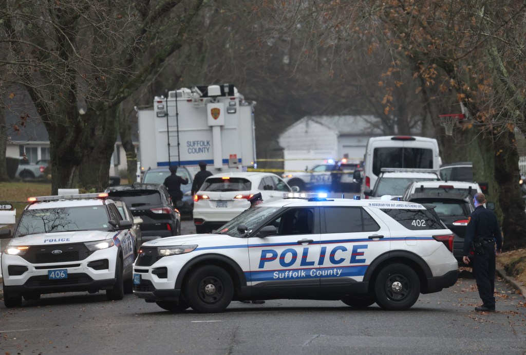 Suffolk County police vehicles with flashing lights and officers at a scene.