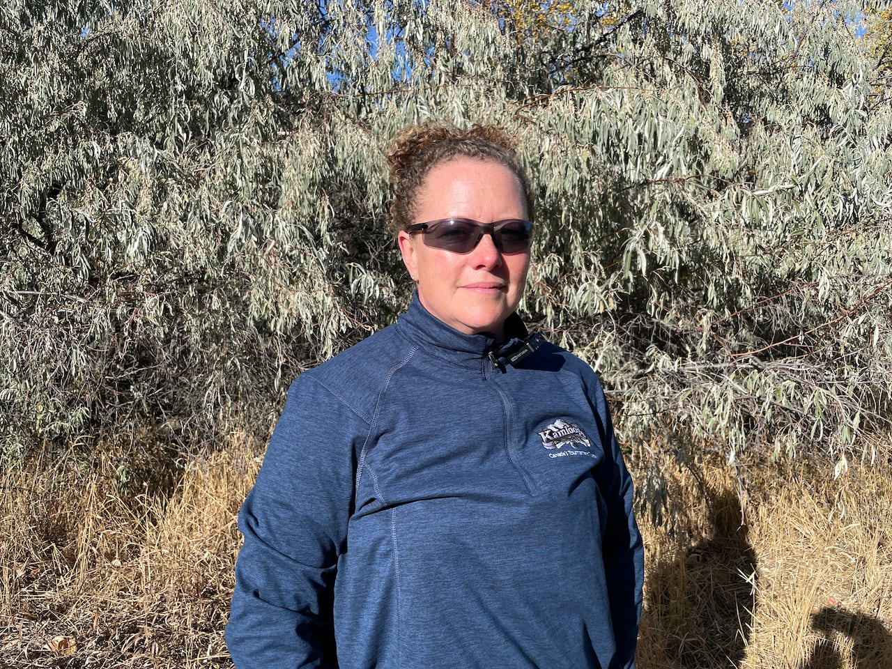 a woman stands in front of a russian olive tree
