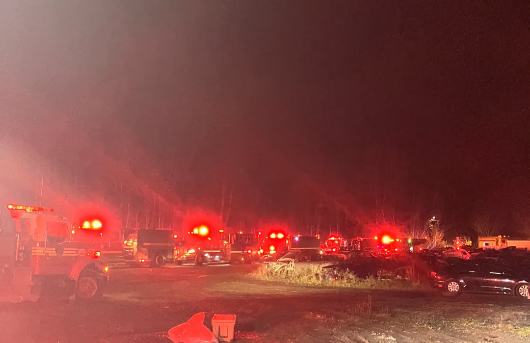 Several fire engines lines up with their lights flashing.