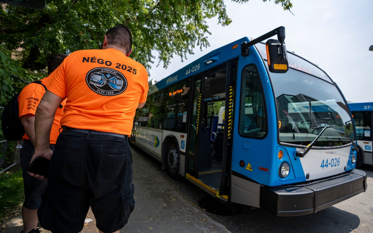Bus drivers beside a bus wear orange shirts