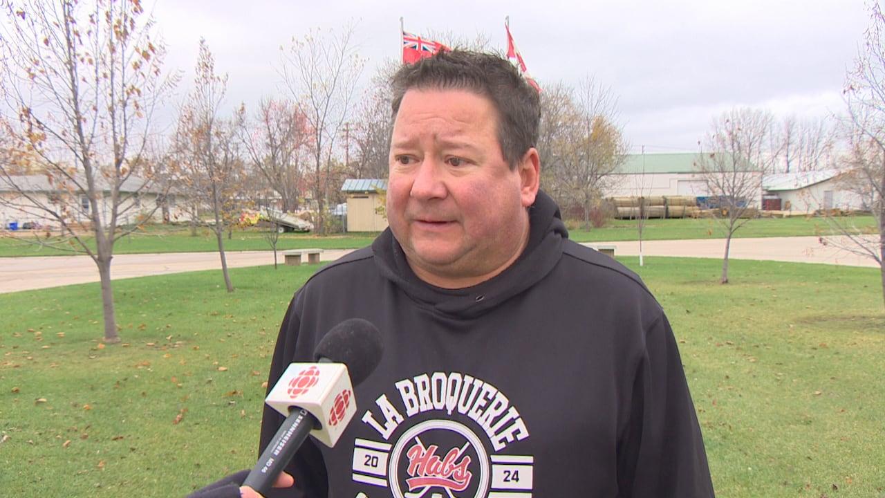 A man with a black , white and red sweater speaking into a microphone
