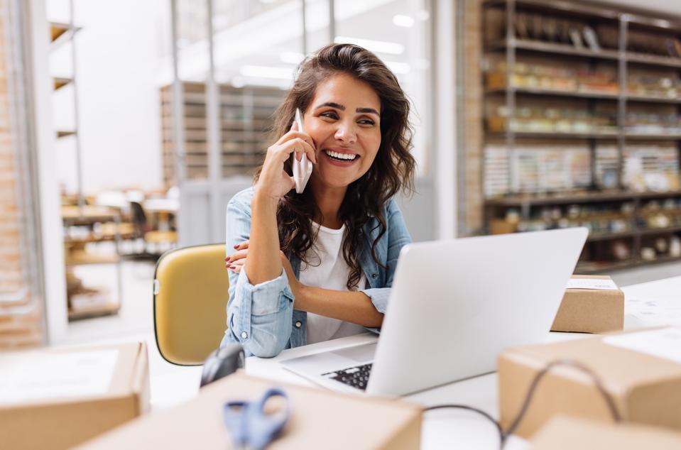 Smiling businesswoman talking on the phone, representing the rise of entrepreneurship.