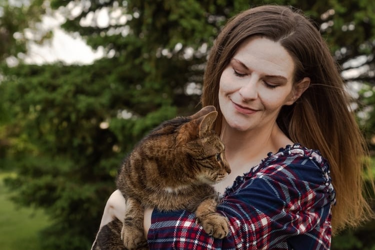 Woman in plaid shirt holds a cat