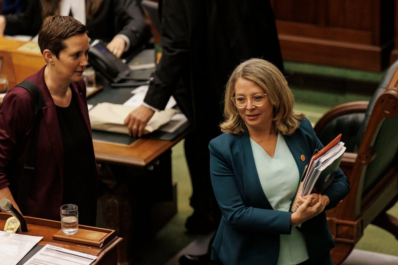 A woman walks with an armful of documents
