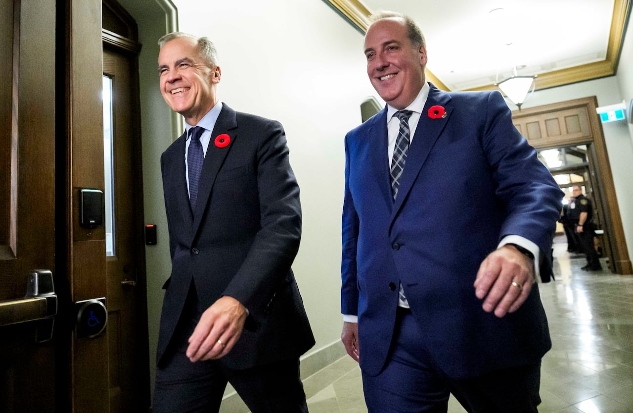 Prime Minister Mark Carney and MP Chris d'Entremont smile as they walk side-by-side towards the Liberal caucus meeting after d'Entremont crossed the floor from the Conservative Party