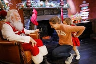 Emery Moore, 3, of Dallas hides behind her mother Casey Moore as she meets Santa Claus in...
