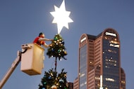 Outside of Dallas City Hall, Rey Cantu of The Christmas Light Company, tops the 35 ft....
