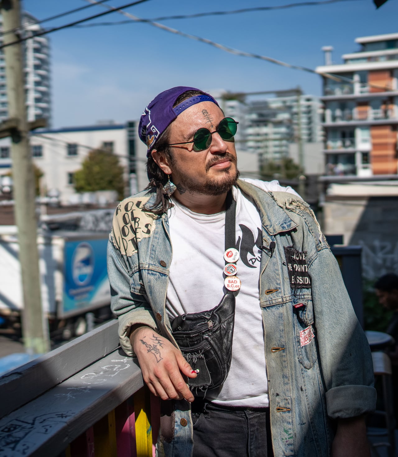 A person wearing sunglasses leans on an outdoor balcony.