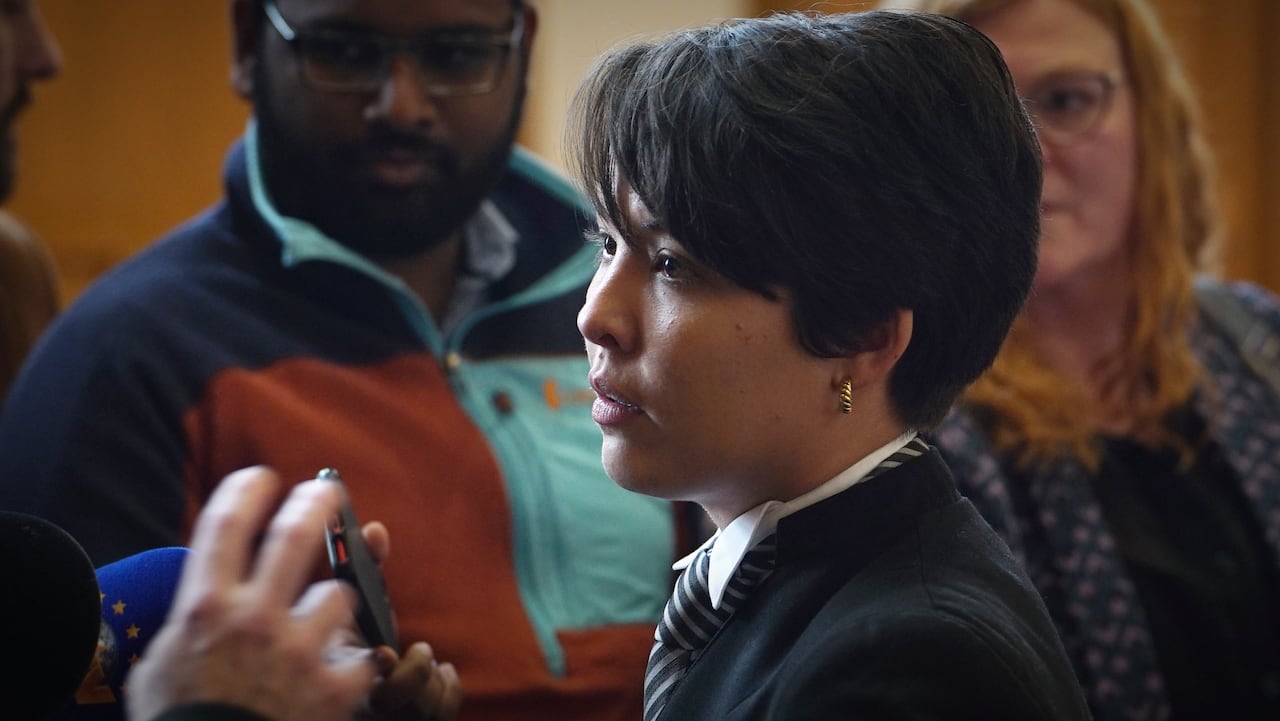 A woman with short black hair speaking to reporters.