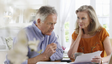 Mature couple with bills sitting at dining table in house