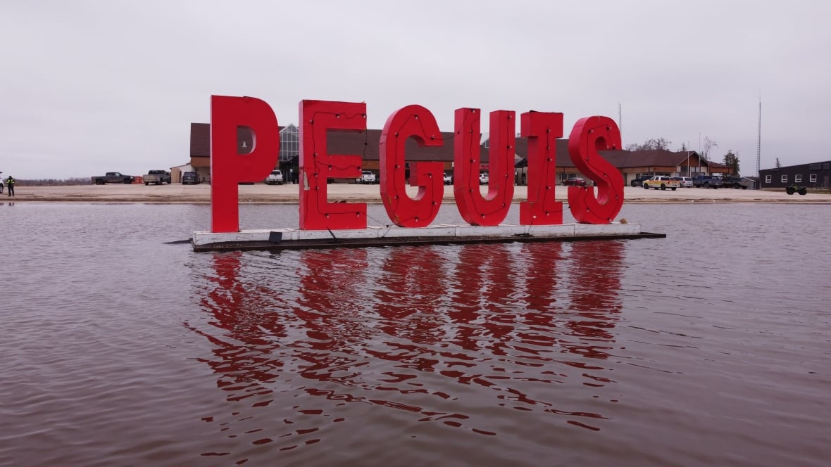 A red Peguis sign standing in a puddle.