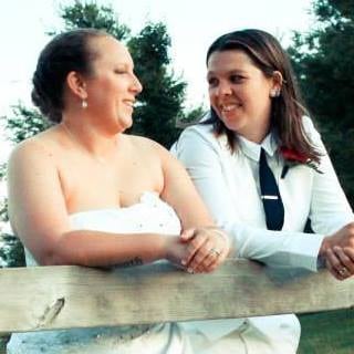 two women in wedding attire smiling at each other