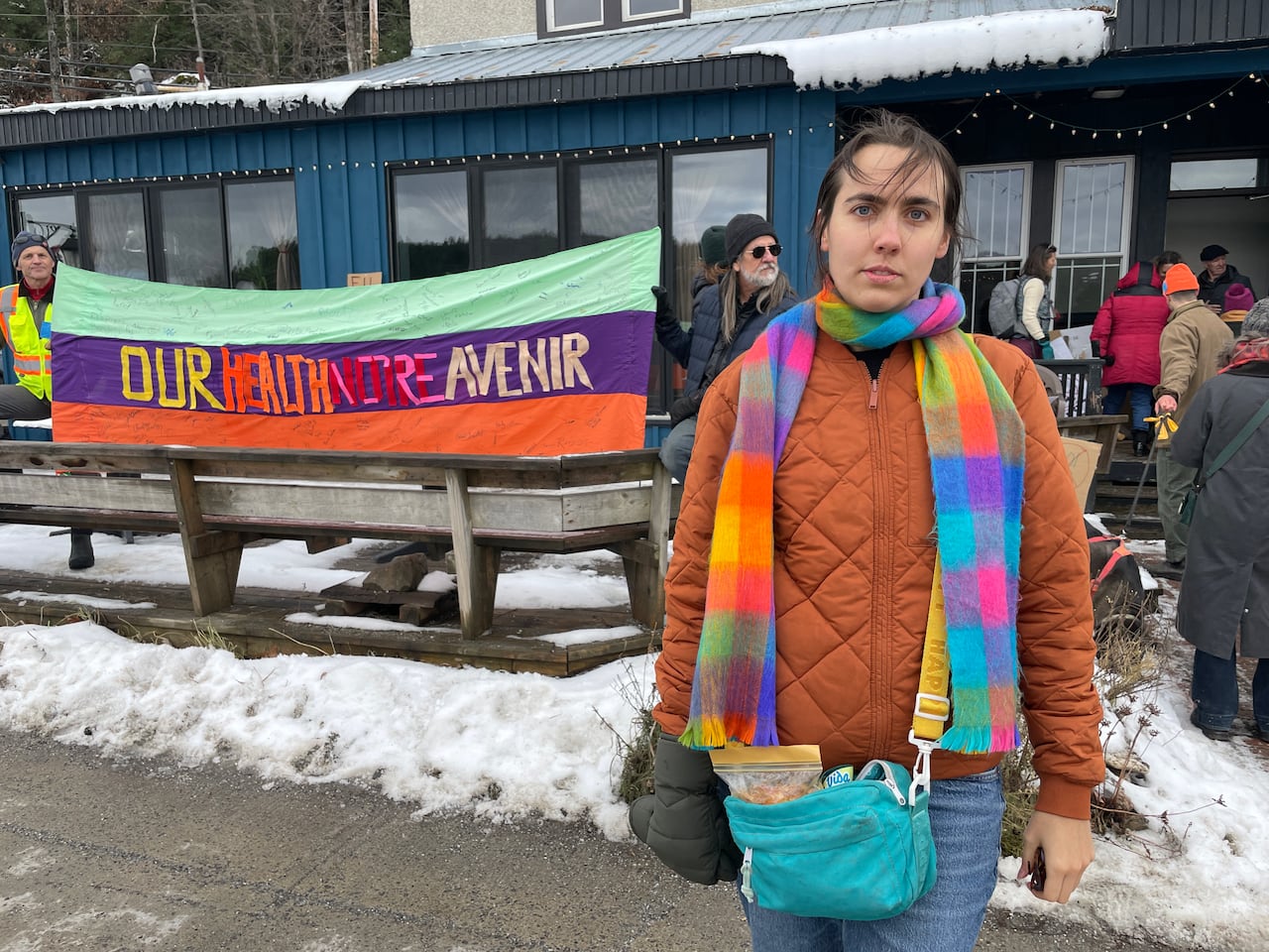 A woman stands in front of a sign saying 'our health notre avenir'