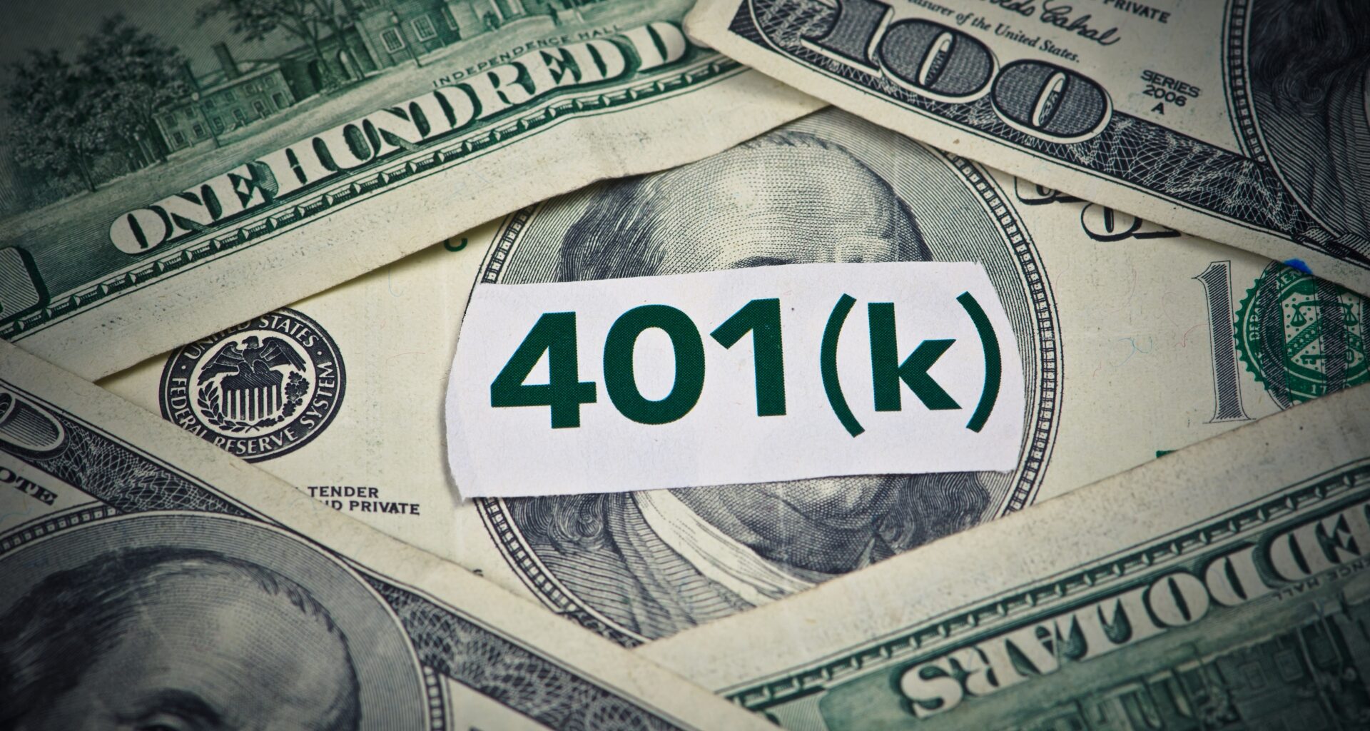 401(k) in bold green text, centered on a white backdrop with neatly stacked hundred-dollar bills underneath.