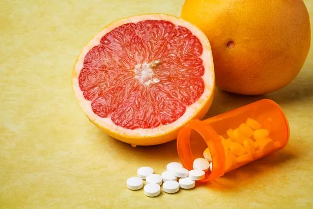 Grapefruit next to a tube of pills