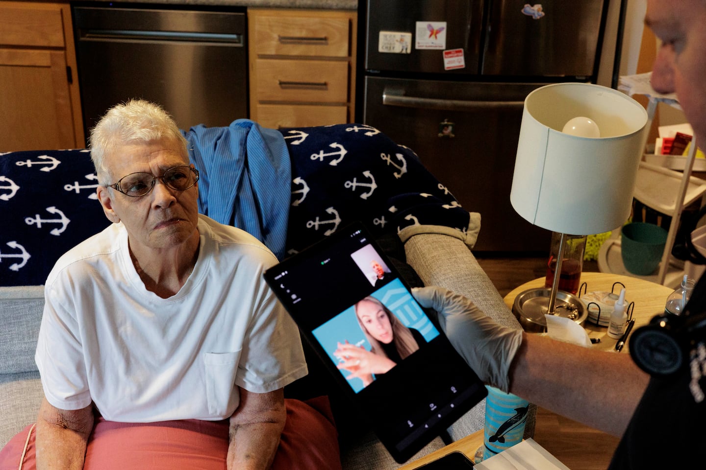 Paula Ward, a 71-year-old South Boston resident enrolled in Mass General Brigham Home Hospital, waits as a program paramedic, Charlie Carey, sets up a video call for her with her MGB physician's assistant during a home visit in September.