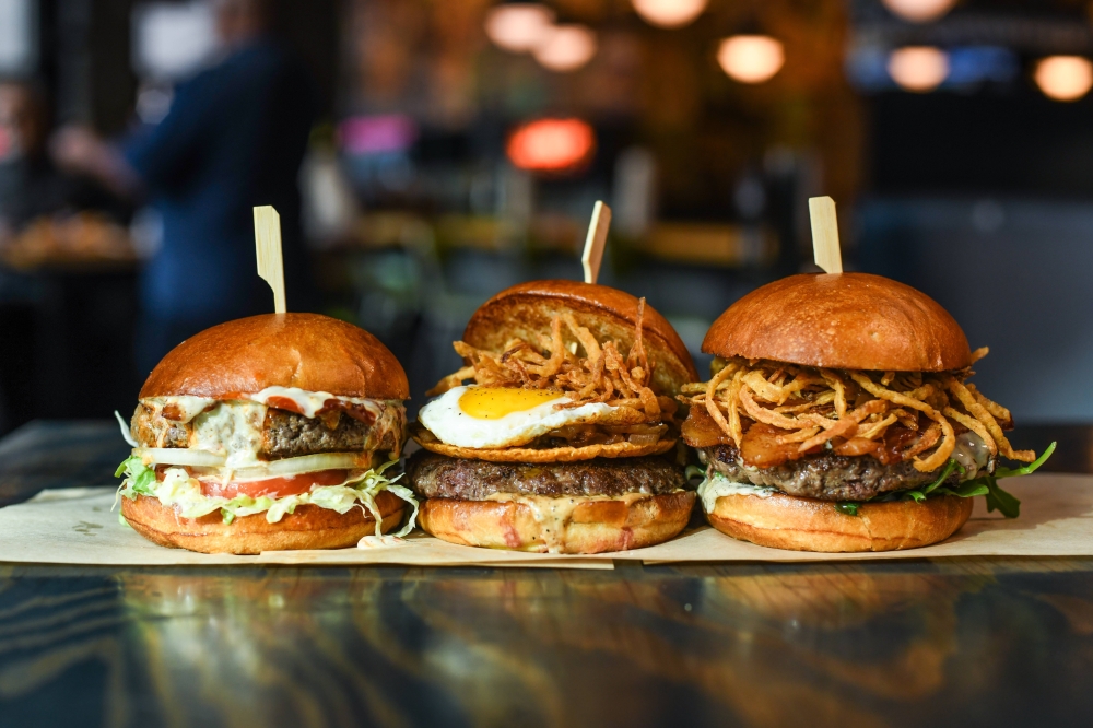Three different types of hamburgers placed side-by-side on a tray.