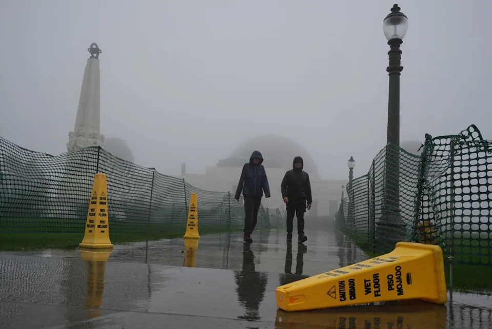 Visitors walk in the rain at the Griffith Park Observatory during a storm in Los Angeles. (AP Photo/Damian Dovarganes)
